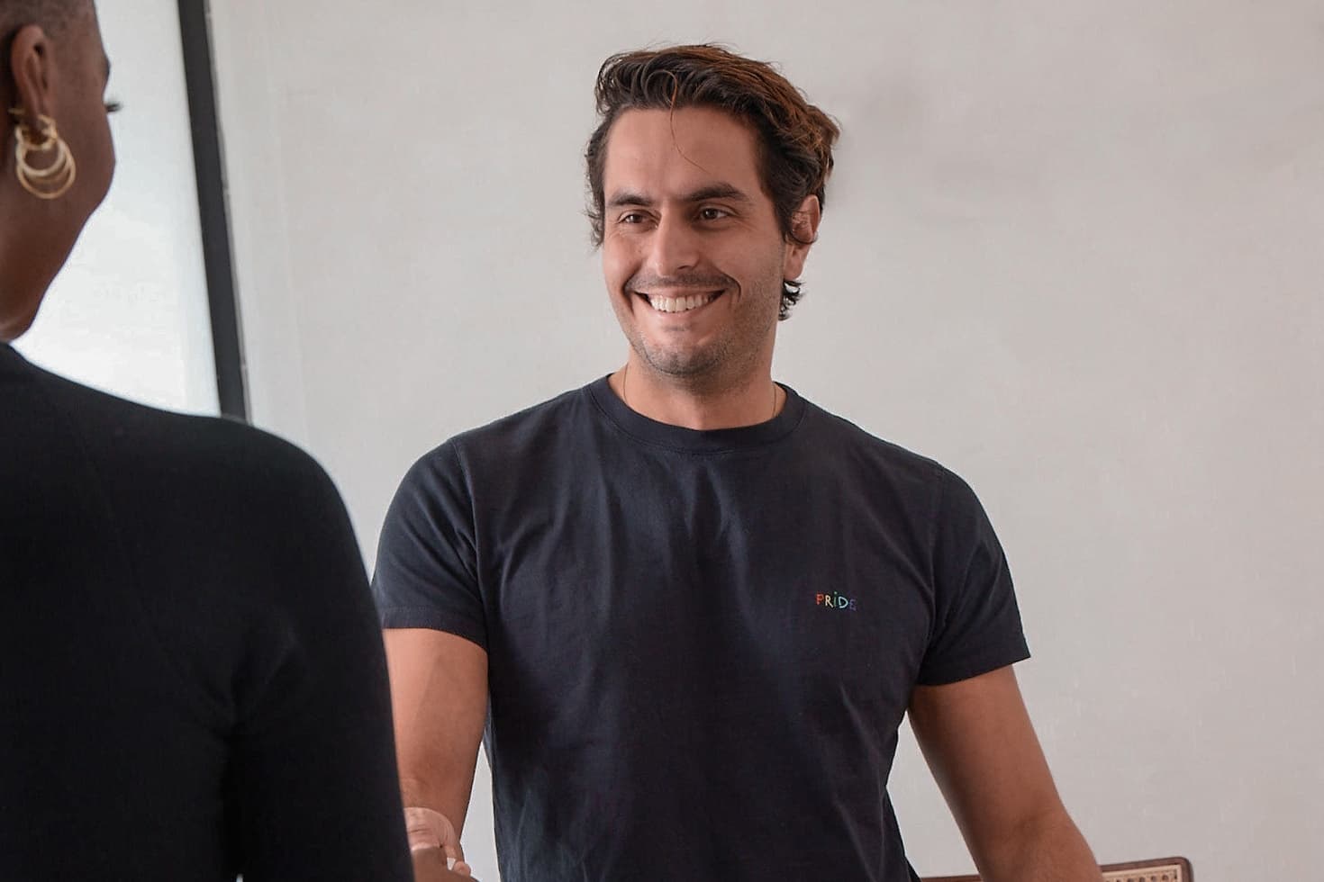 A salon stylist smiles as he greets a client.